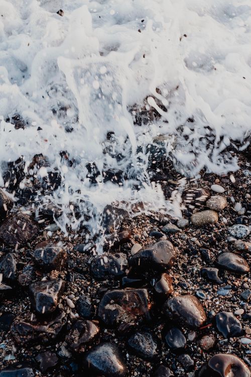 Free Dynamic waves hitting a rocky beach, capturing natural textures and energy. Stock Photo