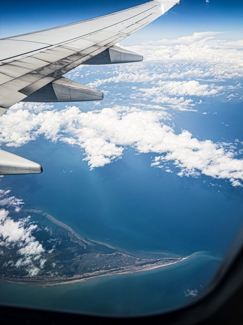 Free Dramatic aerial view from airplane window over coastline and ocean. Stock Photo