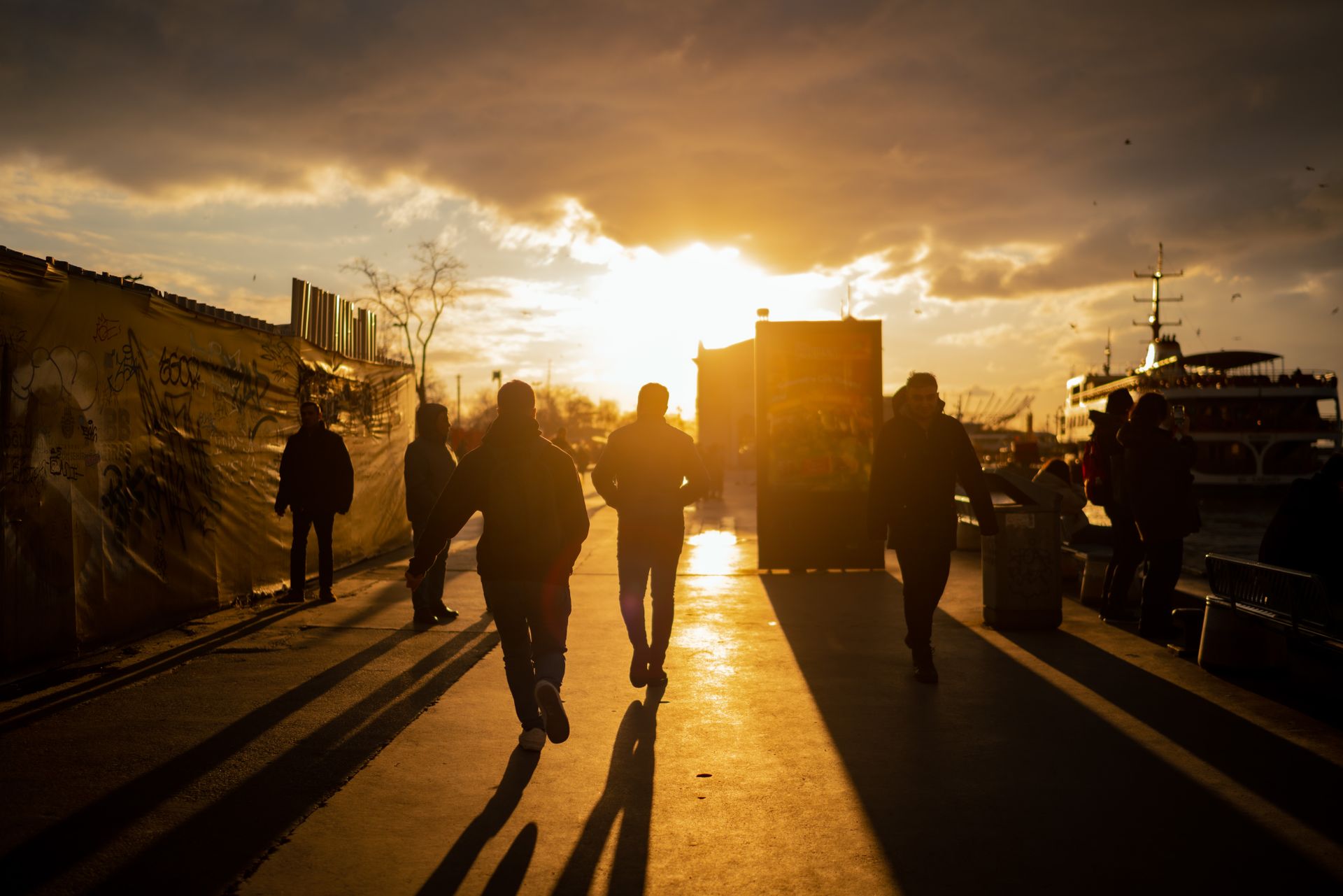Dramatic urban sunset with silhouetted people walking on a bustling street.
