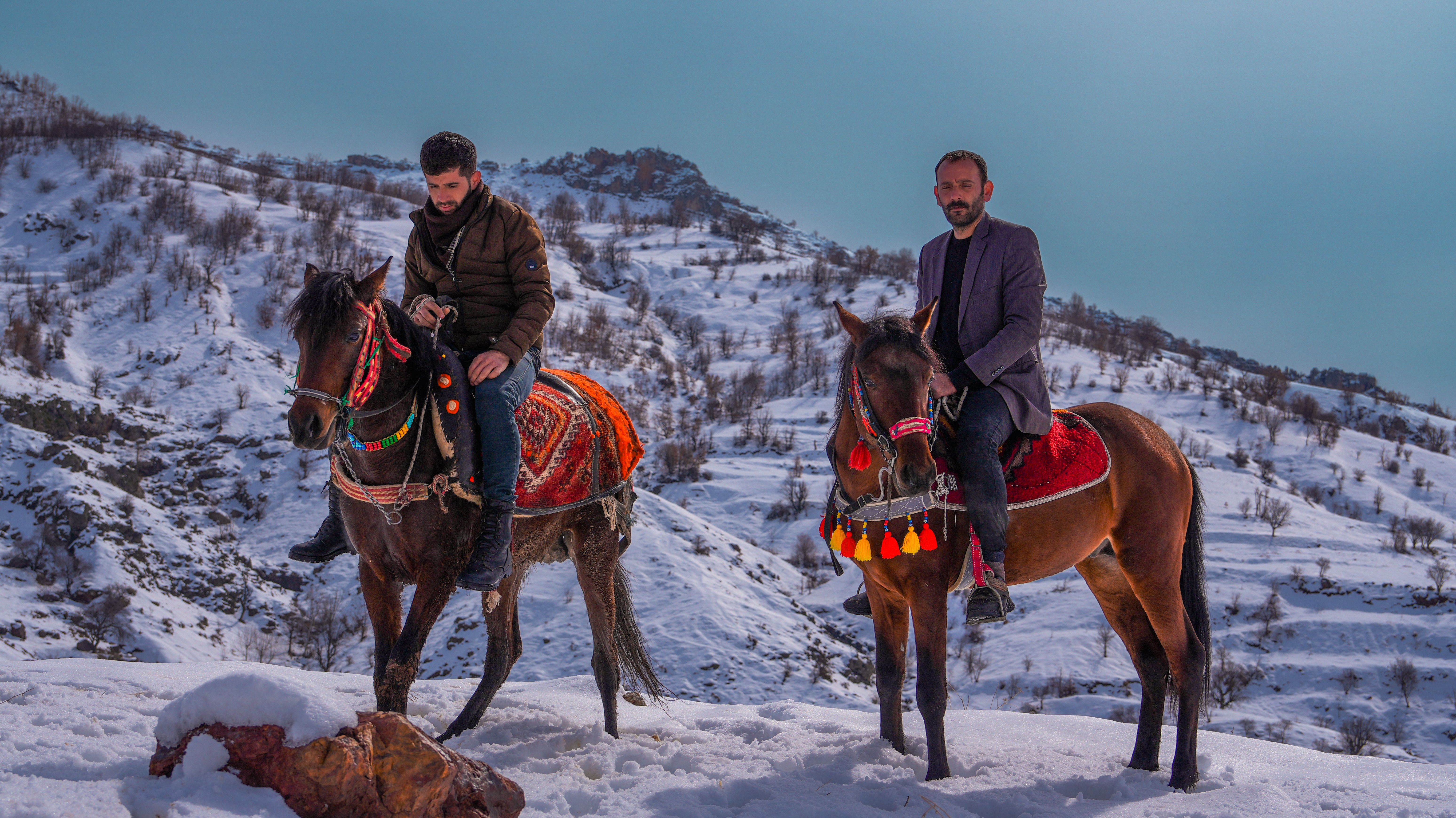 Two Riders on Decorated Horses in Snowy Mountains · Free Stock Photo