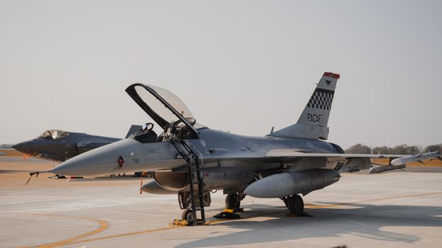 A military fighter jet stationed on an open runway during an air show, showcasing advanced aviation technology.
