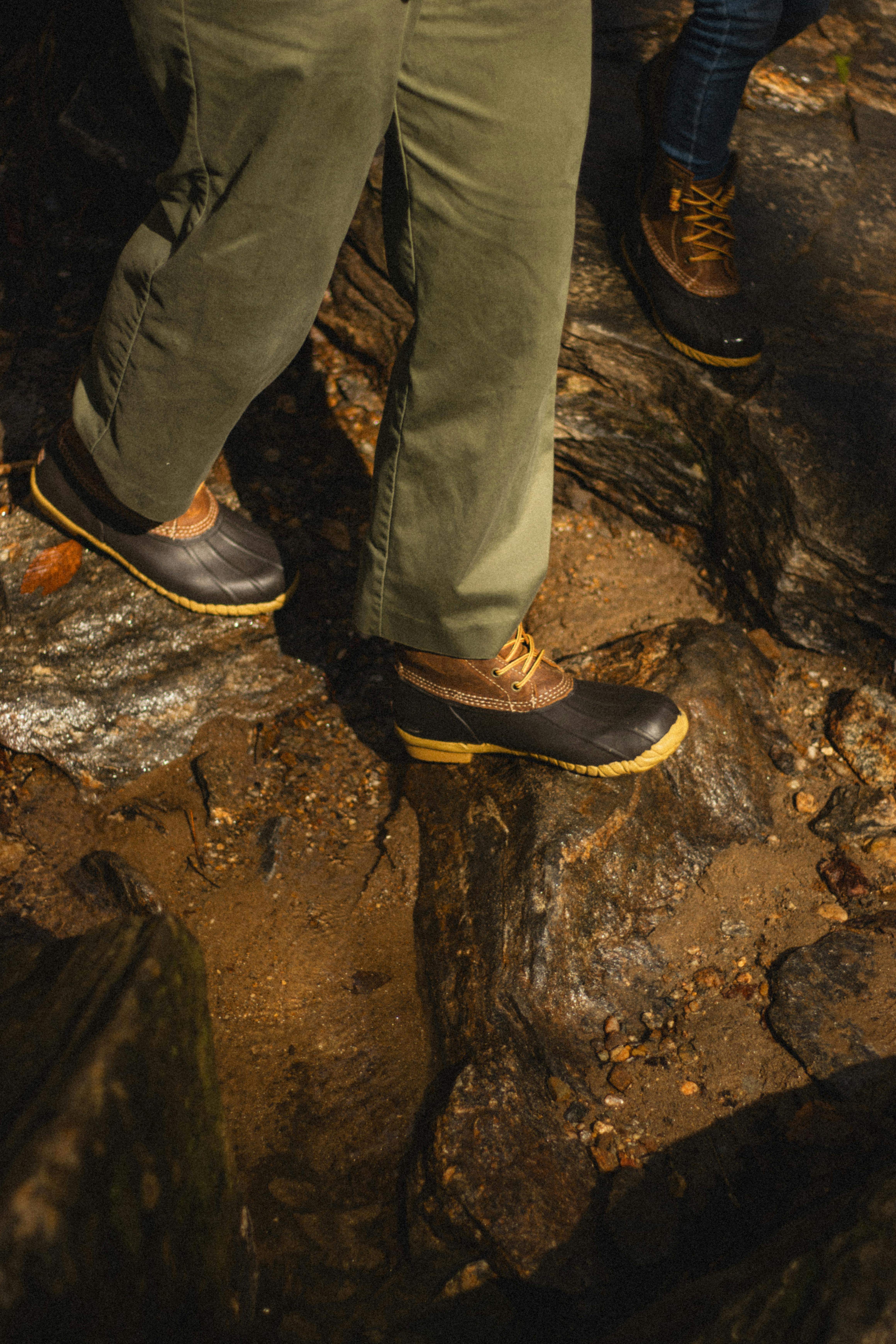 Close-up of two people hiking on rocky terrain with rugged boots.