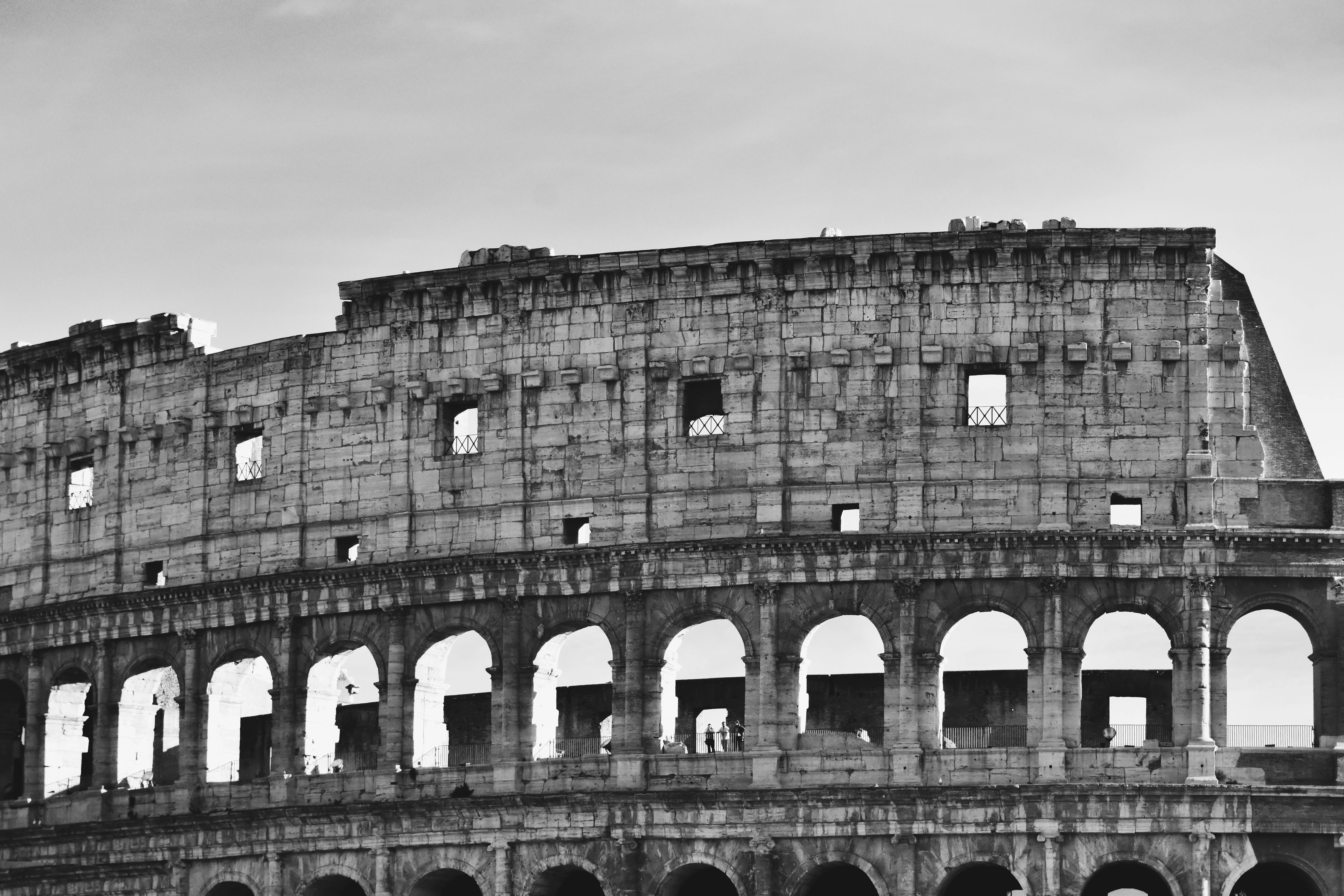 Ilmainen Vangitseva mustavalkoinen valokuva Rooman historiallisesta Colosseumista, joka esittelee sen majesteettista arkkitehtuuria. Kuvapankkikuva