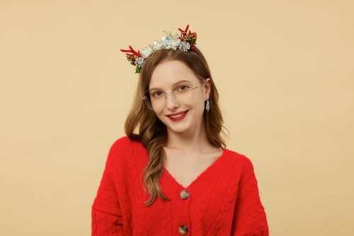 Free Smiling woman wearing glasses and a festive floral headband against a neutral background. Stock Photo
