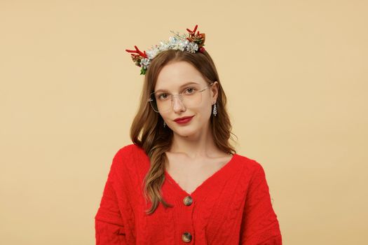 Portrait of a woman in a red sweater with glasses and festive headpiece.