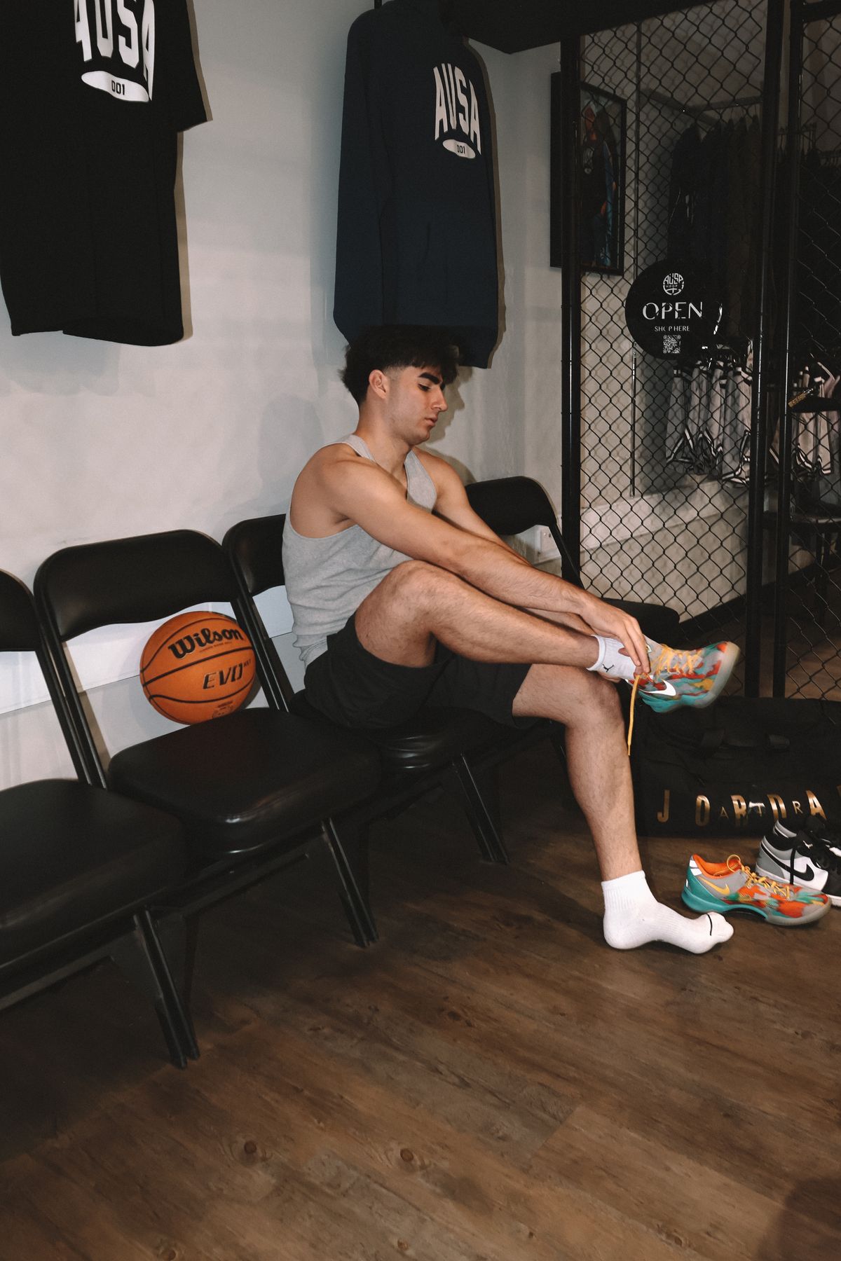 Young man lacing up sneakers in a gym locker room before training
