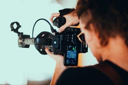 Close-up of a videographer capturing footage with a professional camera setup.