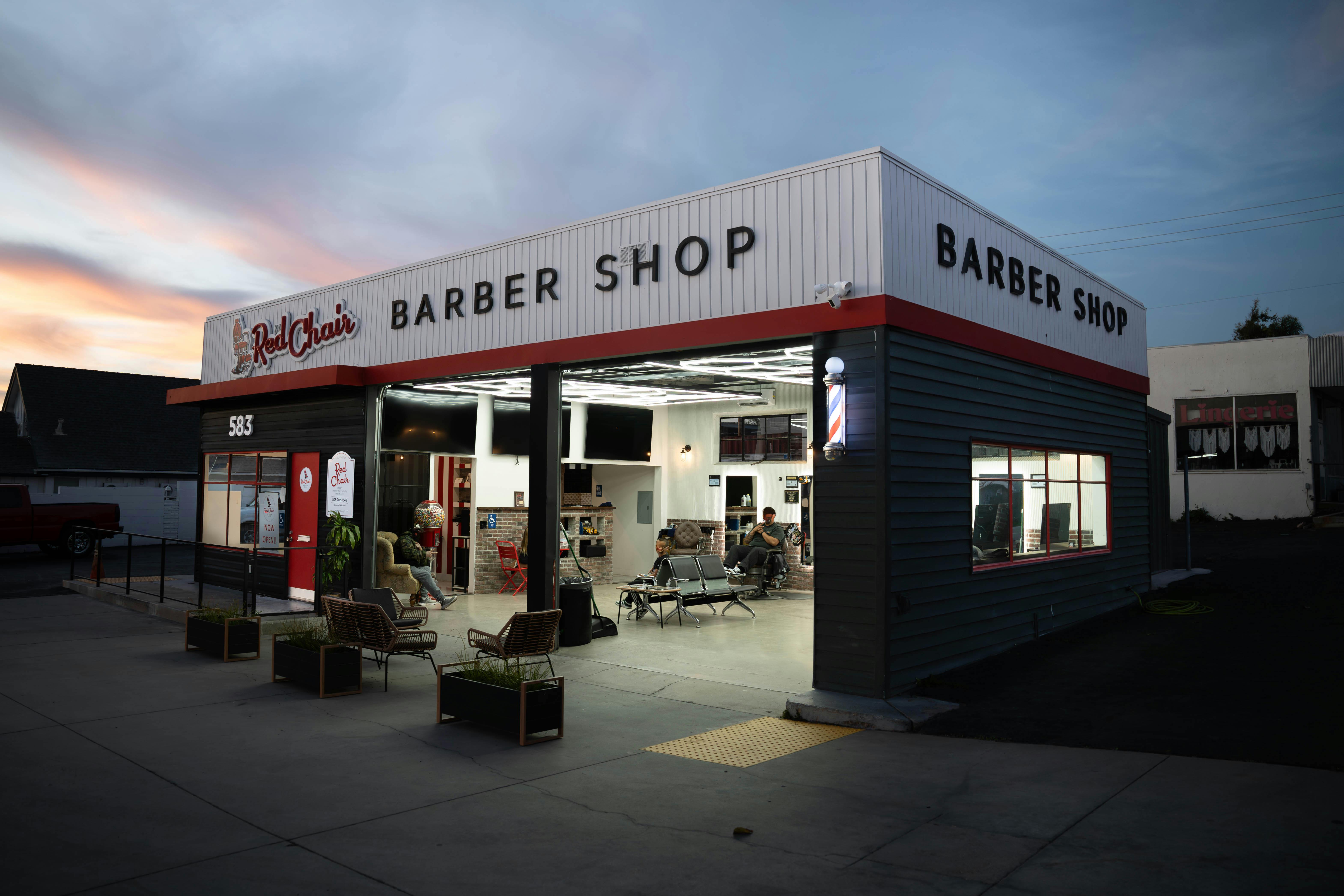Warm evening view of a barber shop with customers inside, creating a welcoming atmosphere.