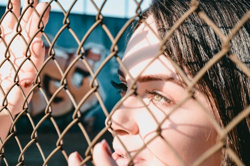 Femme S'appuyant Sur Une Clôture à Mailles De Chaîne