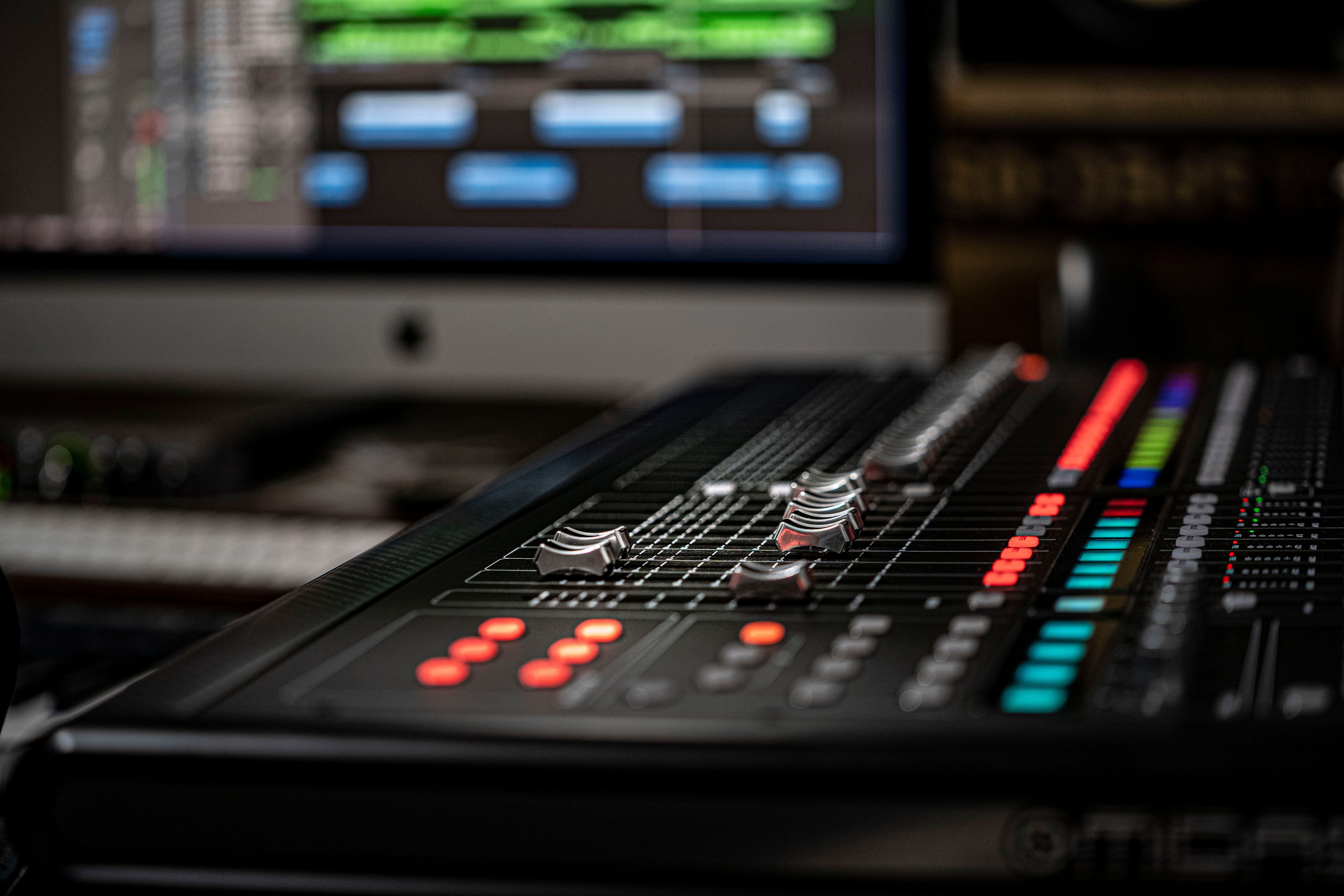 Detailed photo of an audio mixer with vibrant lights and screens in a professional studio.