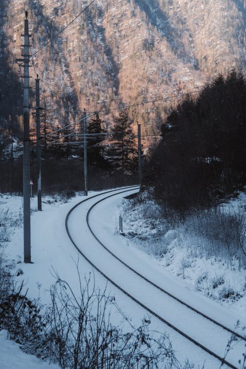 Free Serene railway tracks winding through a snowy mountainous landscape under clear winter skies. Stock Photo