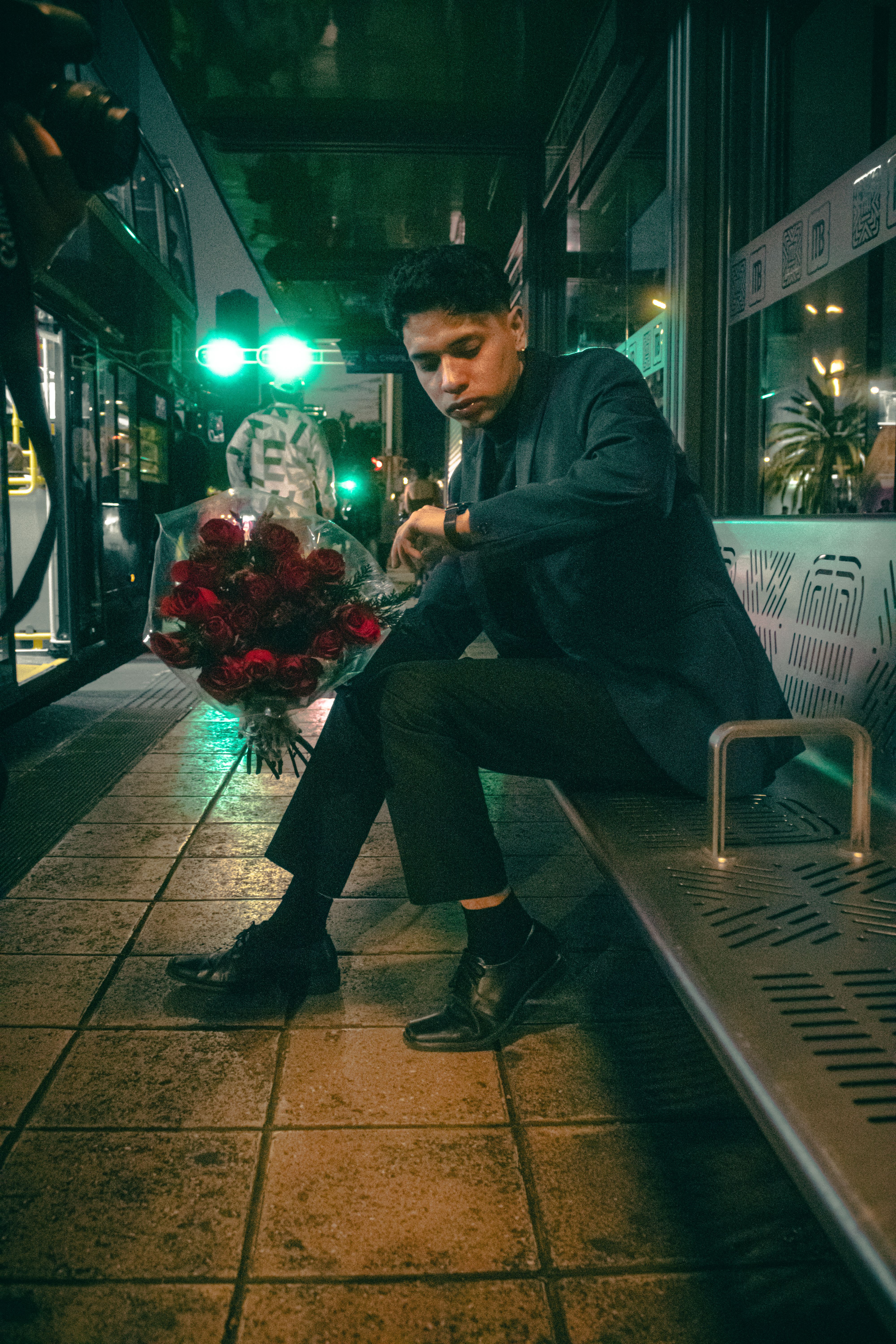 Man Waiting at Night Bus Stop with Roses · Free Stock Photo