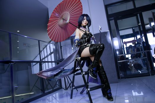 Elegant cosplay character posing with red umbrella indoors, showcasing creativity.