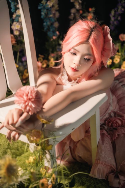 Free Pink-haired woman in floral dress resting in a serene, vibrant flower garden. Stock Photo