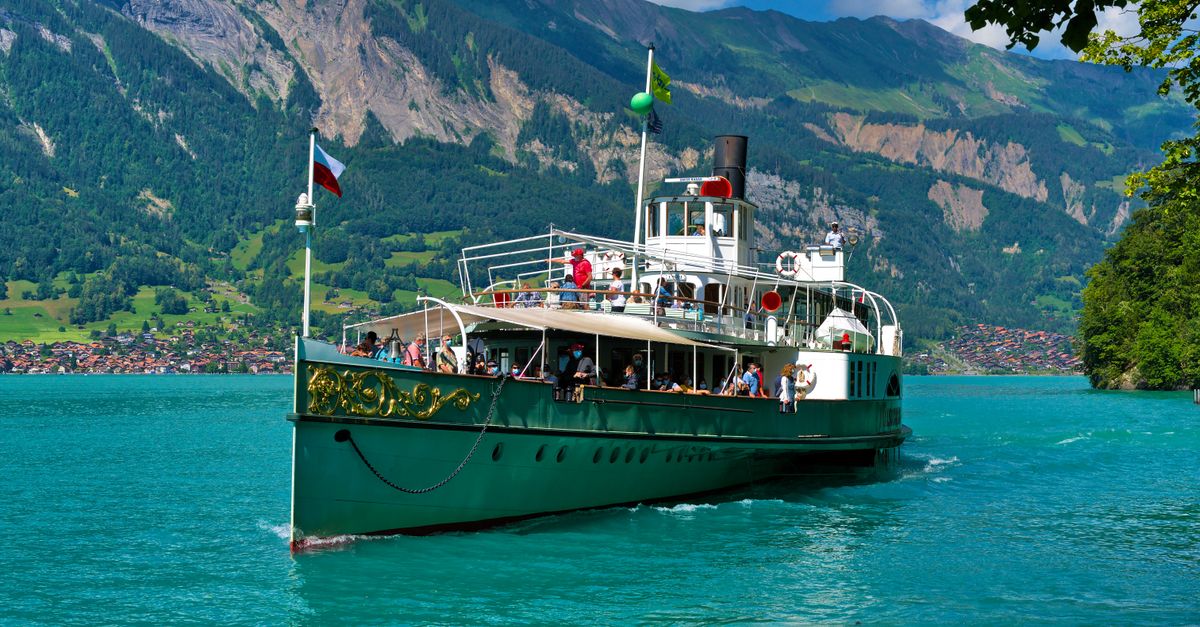 Um pitoresco veleiro navegando pelas águas azul-turquesa do Lago Brienz, com vista para os Alpes Suíços em Iseltwald, Suíça.