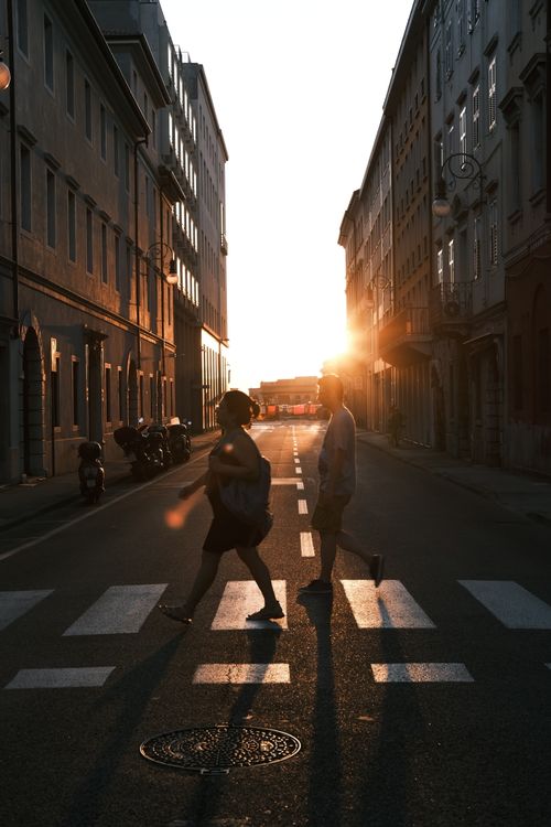 Free Artistic street photo of silhouettes crossing a city street at sunset in Trieste, Italy. Stock Photo