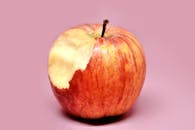 Red Apple with Bite on Pink Background