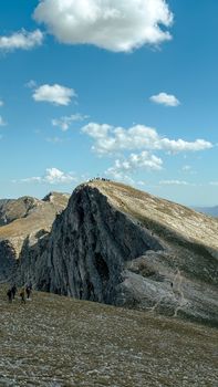 Scenic view of hikers on a rocky mountain summit under a clear blue sky.