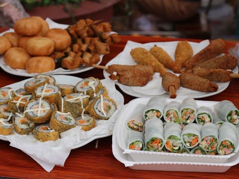 Delicious assortment of Asian street food including sushi rolls and fried snacks displayed on a table.