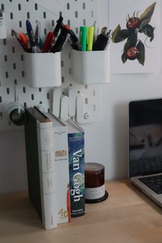 A neat desk with books, pens, and a laptop, ideal for a creative workspace.