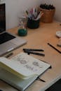 Artistic Workspace with Sketchbook and Laptop