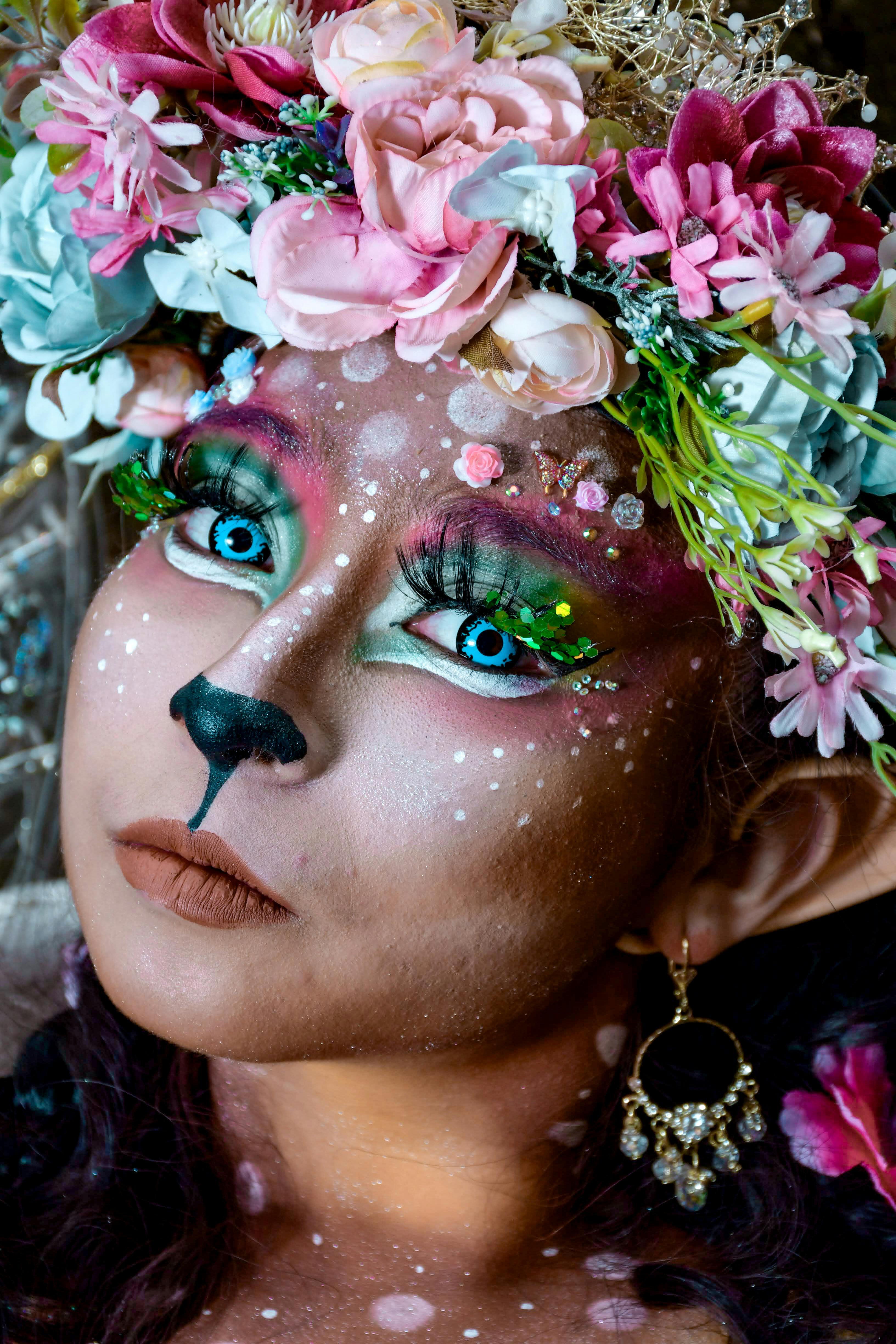 Close-up of a vibrant fantasy deer makeup look with a floral crown.