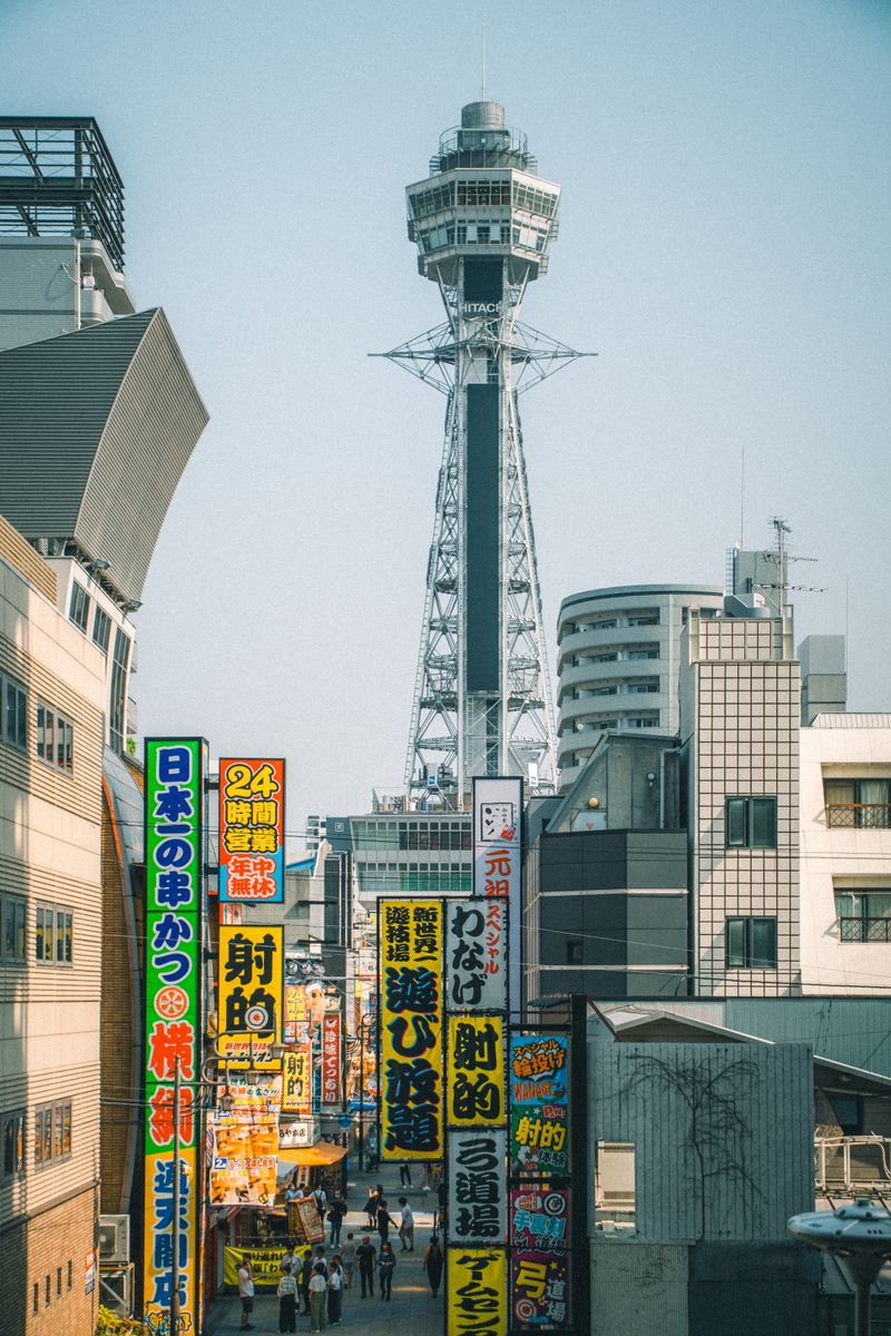 Colorful urban street scene featuring Osaka's iconic Tsutenkaku Tower surrounded by vibrant signage.