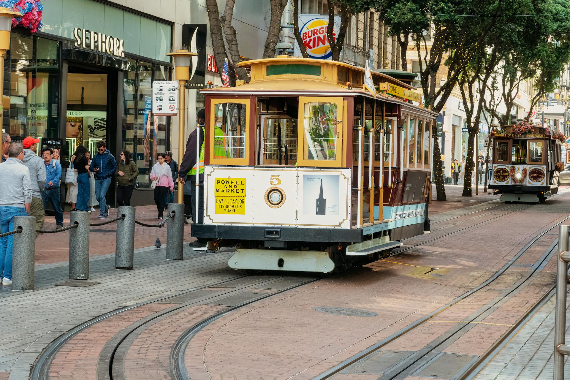 San Francisco cable car traveling through bustling downtown area, showcasing city life.