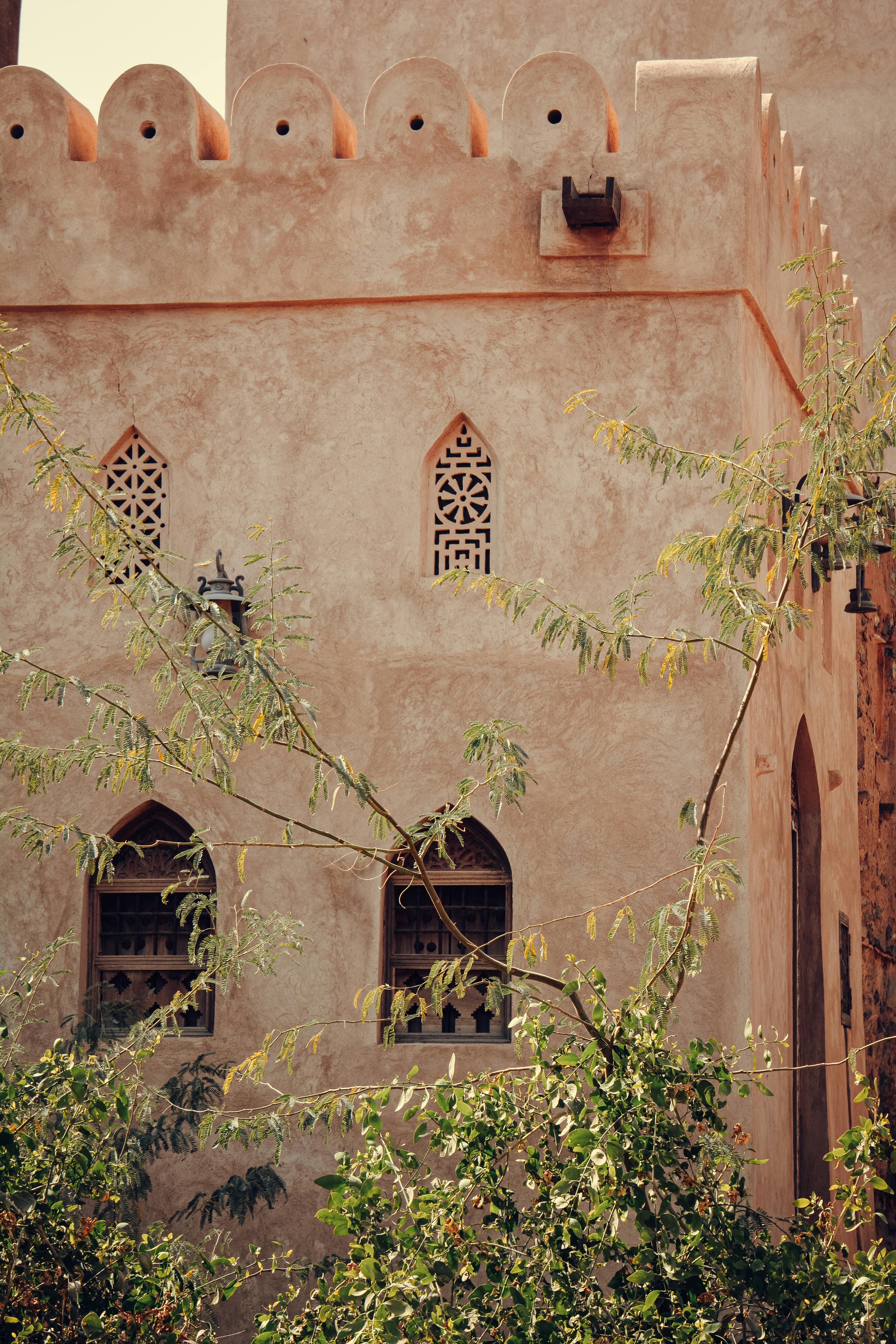 Vintage style Middle Eastern building with intricate arch windows and natural foliage.