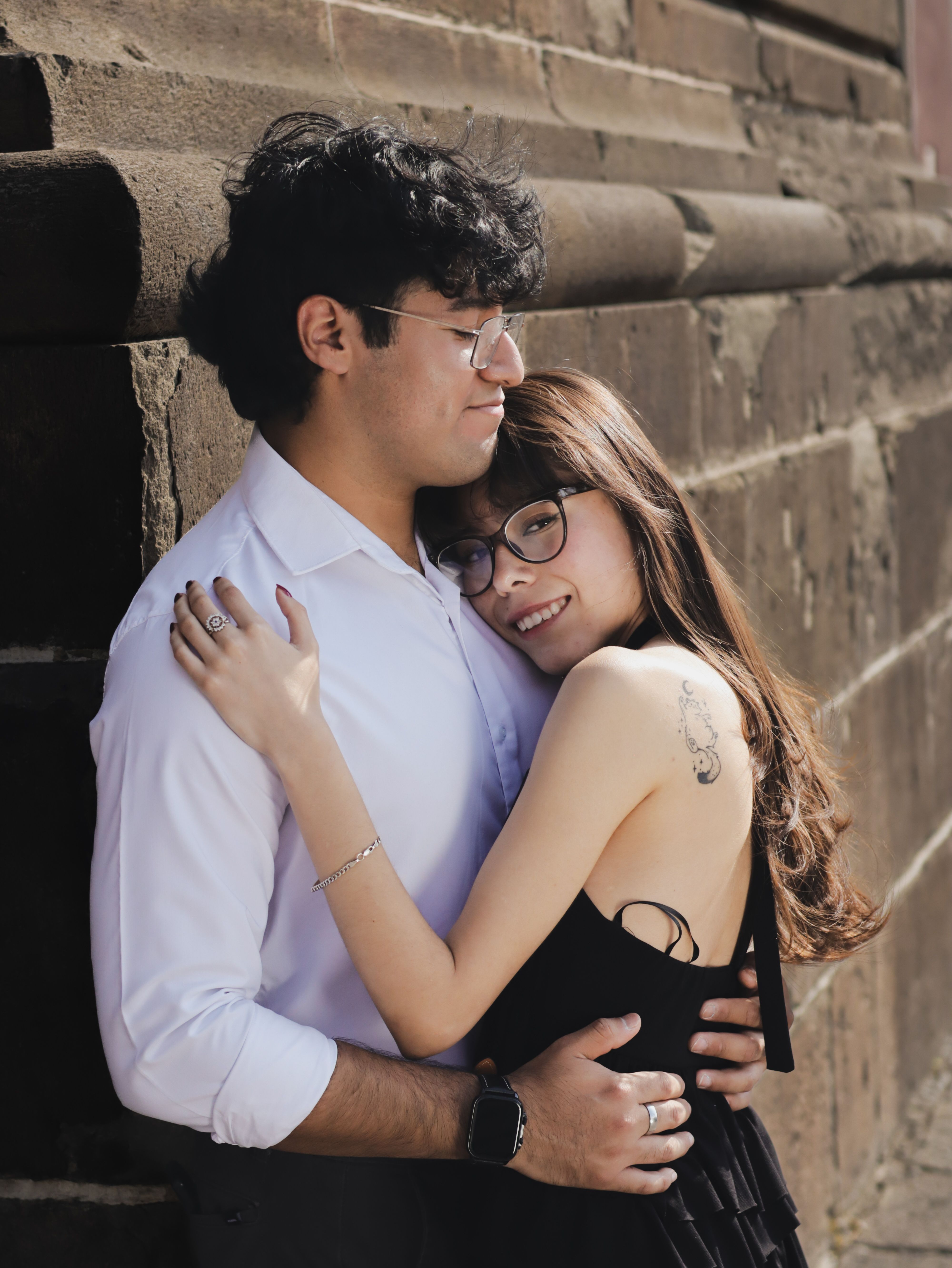 Affectionate young couple embraces in a warm, outdoor setting.
