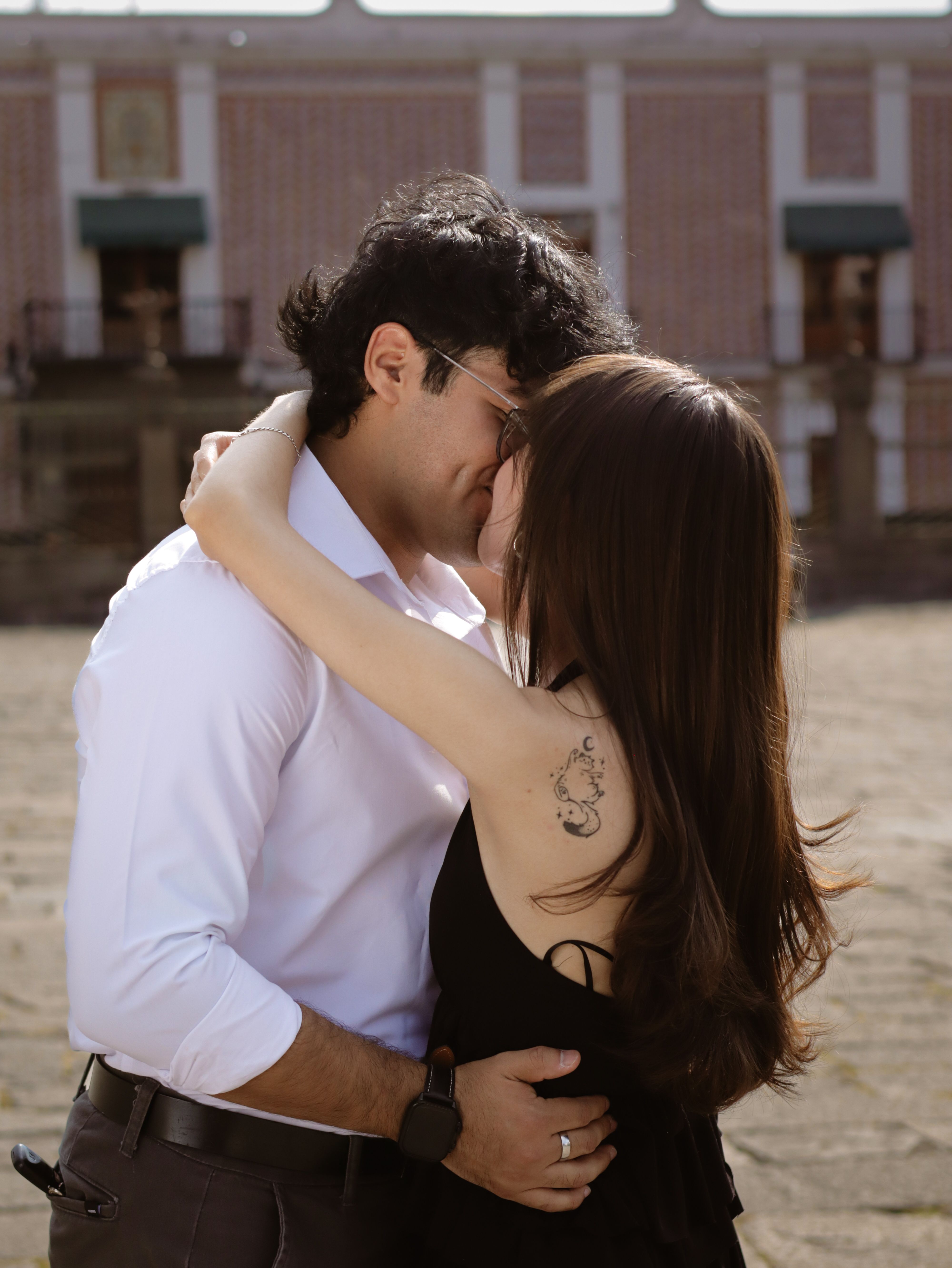 A young couple sharing a romantic embrace outdoors on a sunny day.