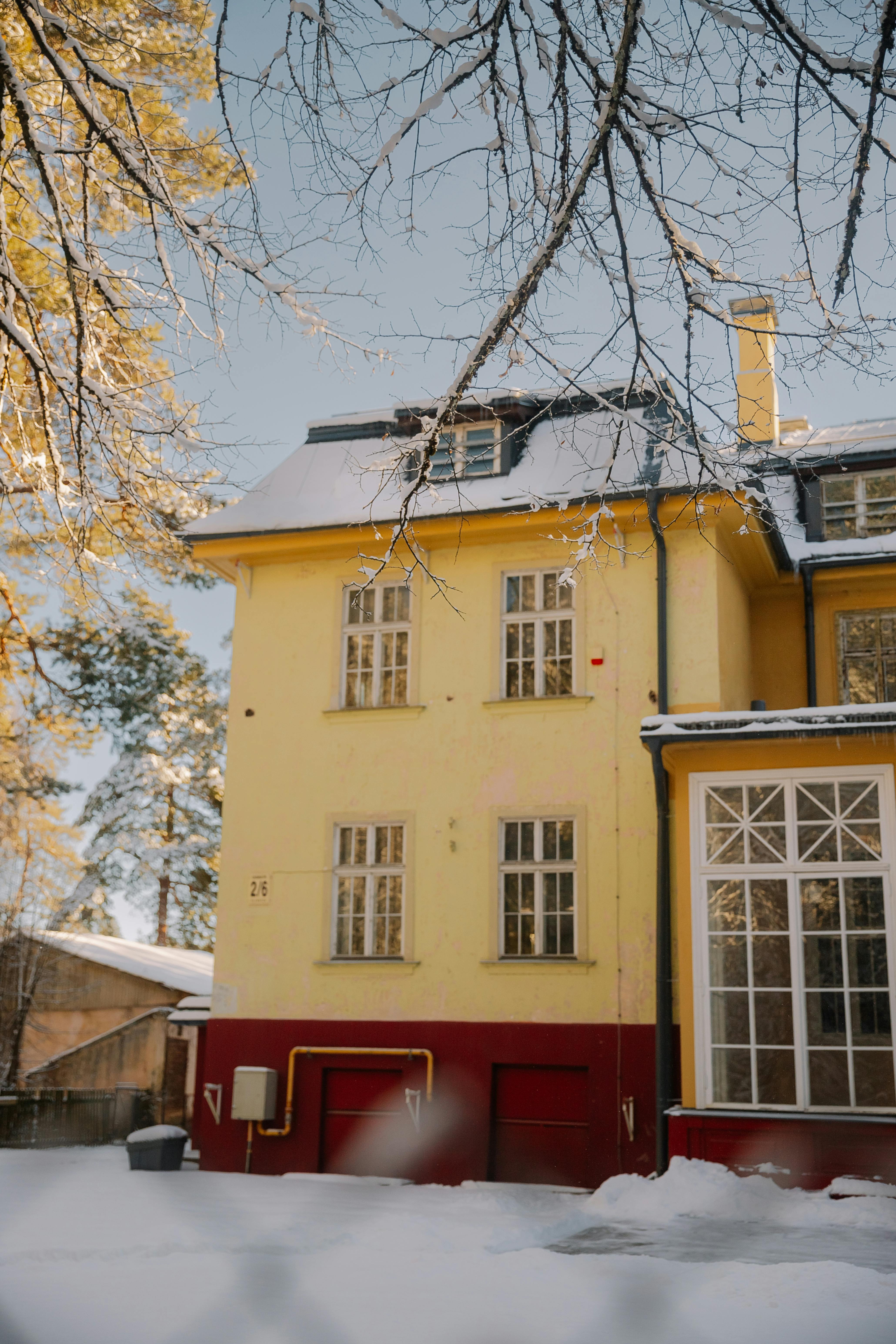 A bright yellow house surrounded by snow in a serene winter setting.