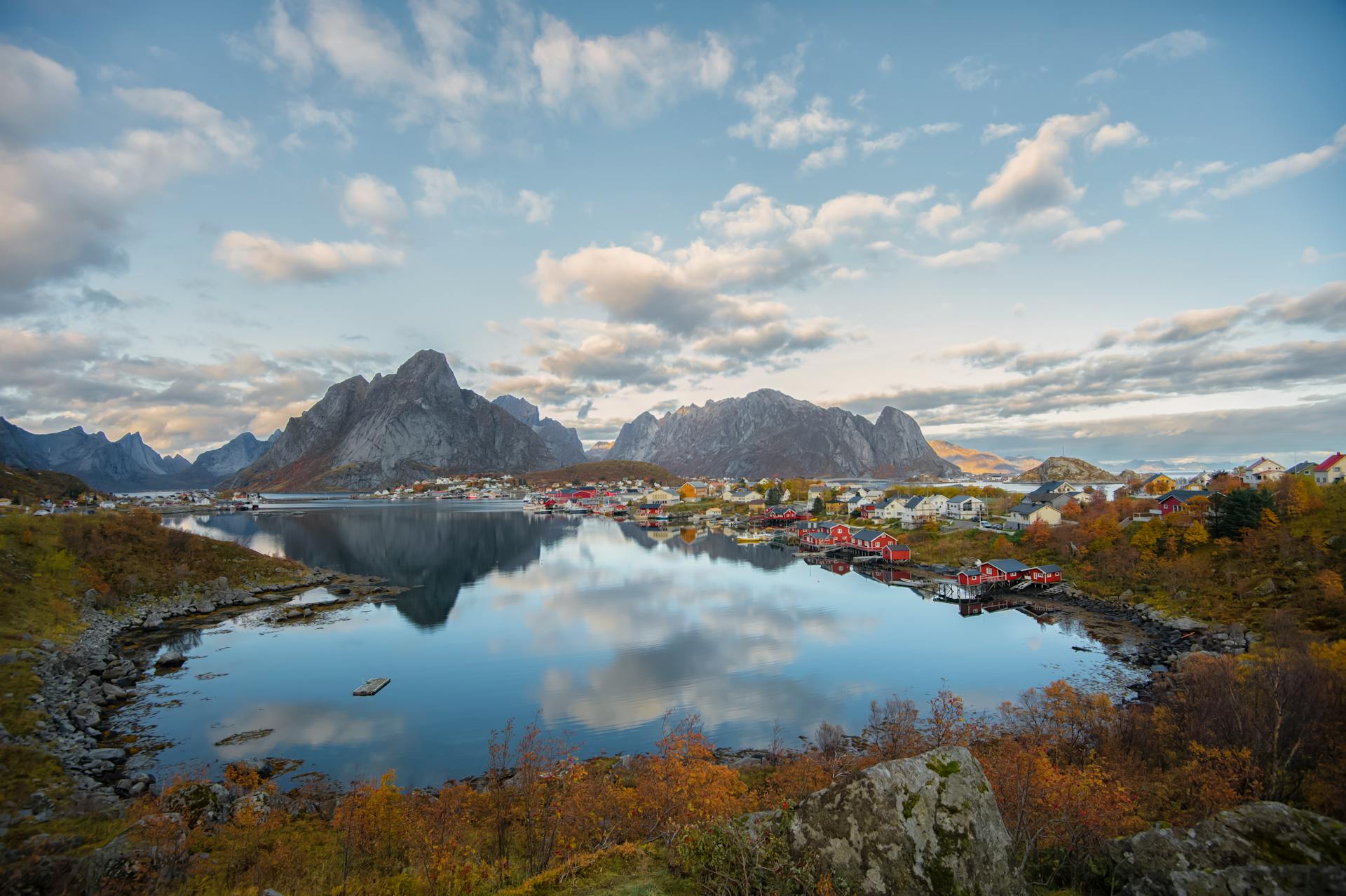 Explore the picturesque Reine village in Norway with dramatic mountains and tranquil waters reflecting autumn colors.