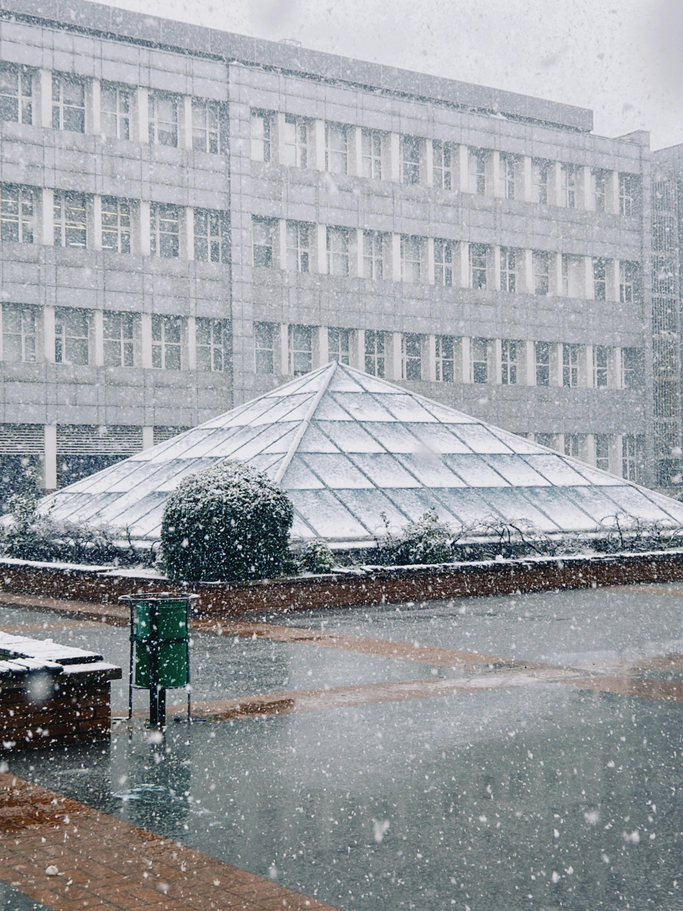 Snowfall Over Pyramidal Glass Structure in Winter · Free Stock Photo