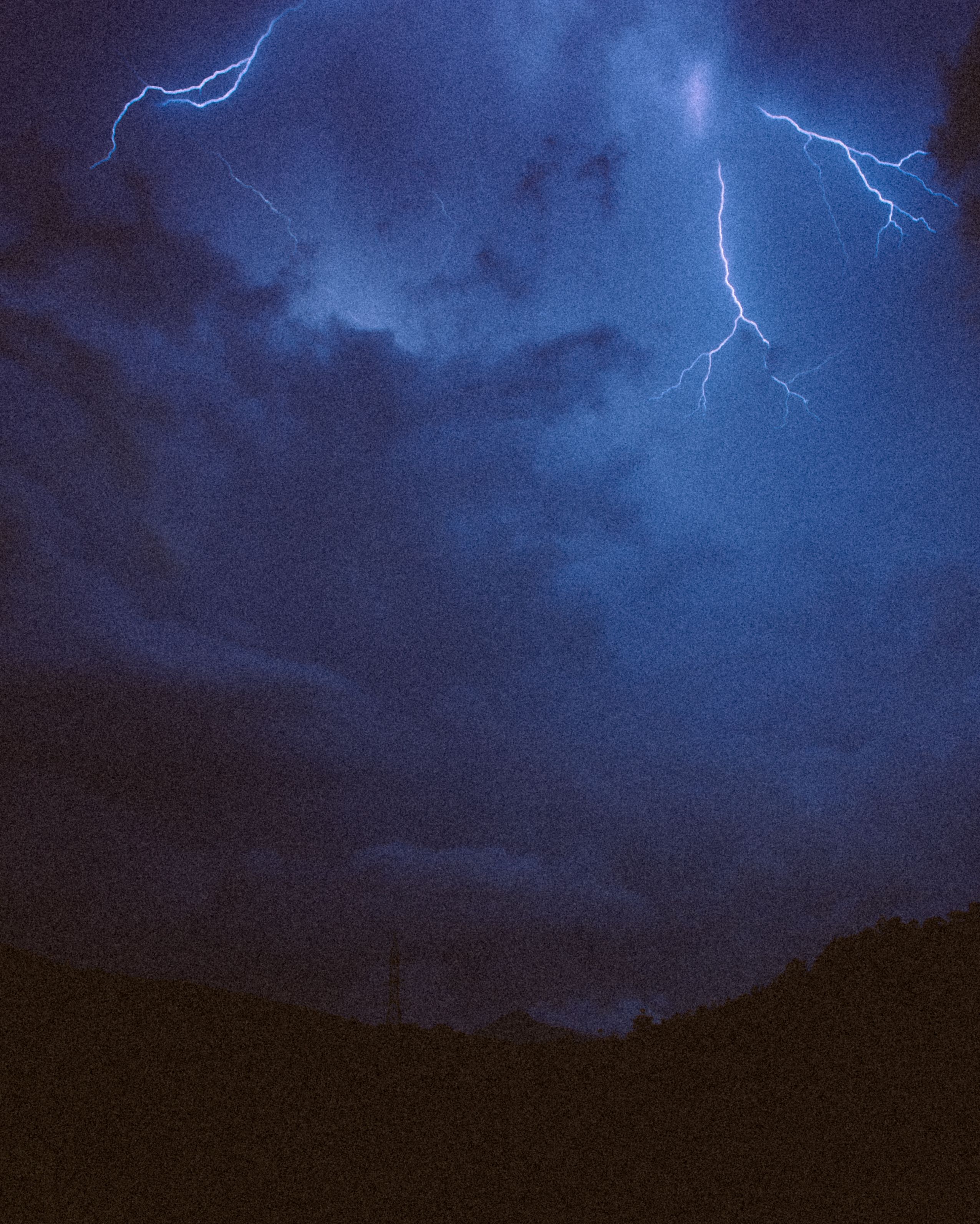 Striking lightning bolt illuminates the dark night sky during a storm.
