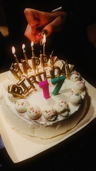 Close-up of a festive 17th birthday cake with candles lit, ready for celebration.