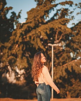 一名年轻女子在绿树成荫的公园里，微笑着享受阳光明媚的一天