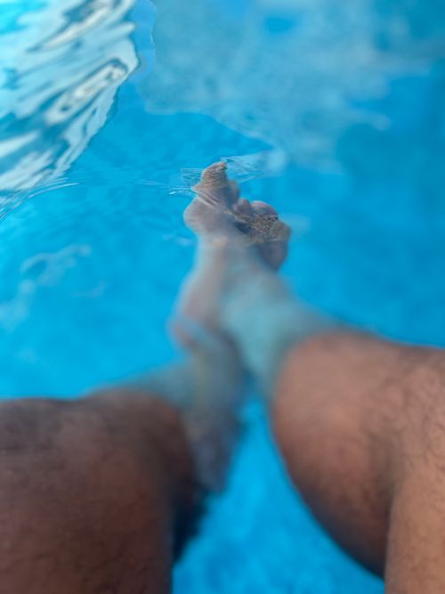 Free Feet submerged in clear blue pool water, capturing a sense of relaxation. Stock Photo