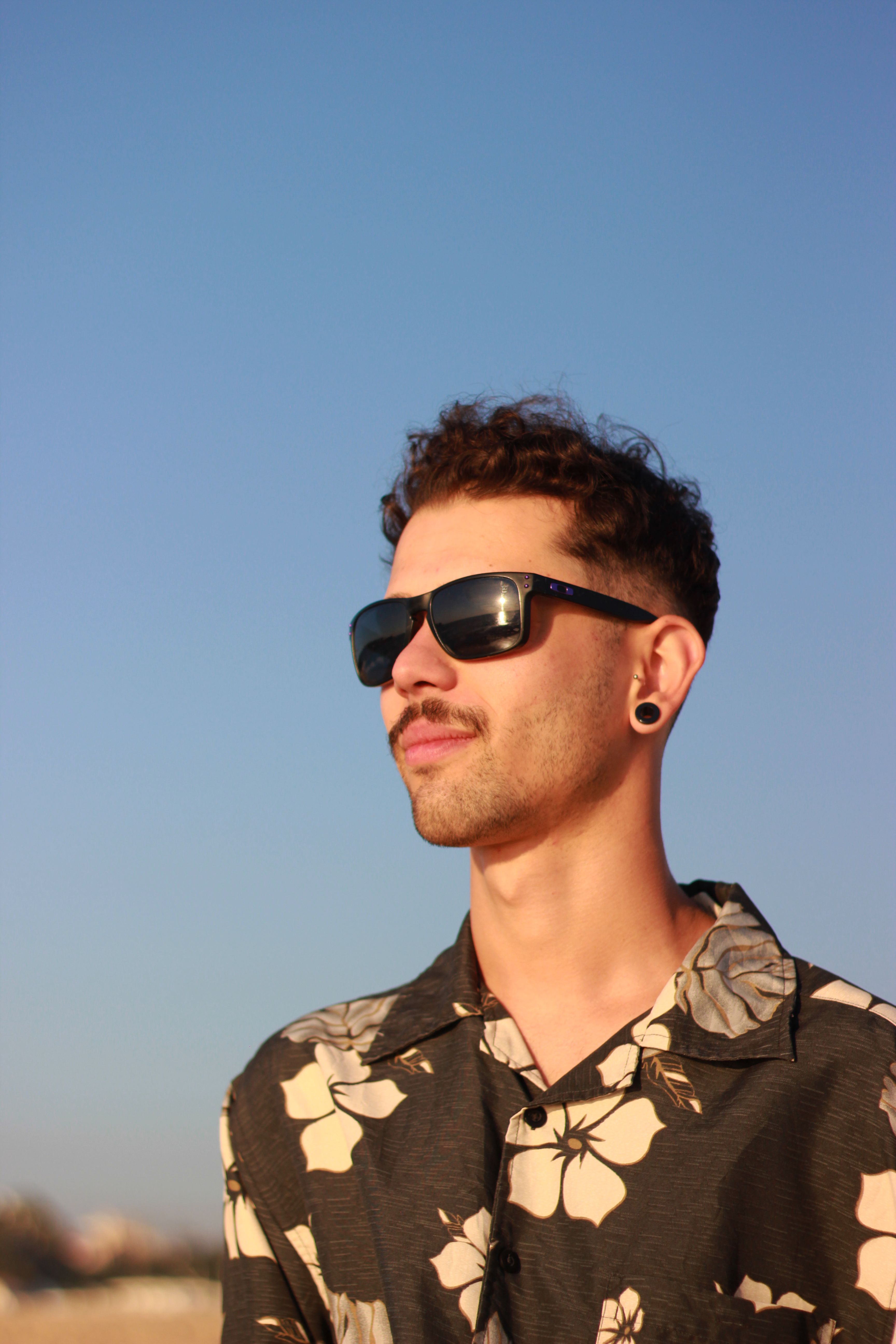 Young man in floral shirt and sunglasses enjoying a sunny day at Nazaré beach.