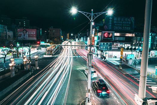 Vibrant city intersection at night with colorful light trails from moving vehicles, capturing urban energy.