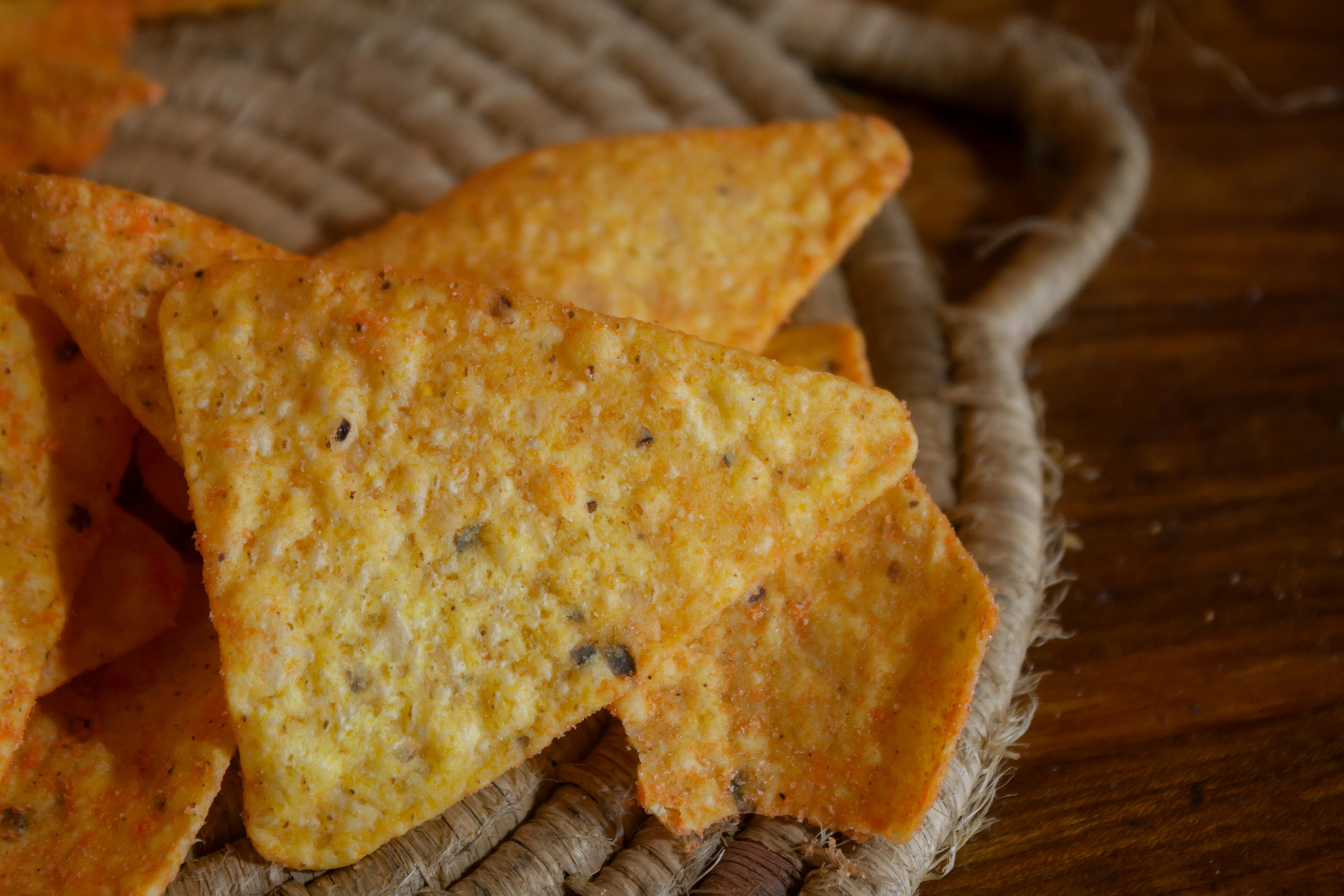 Crispy nacho chips displayed on a rustic woven mat, perfect for party snacks.