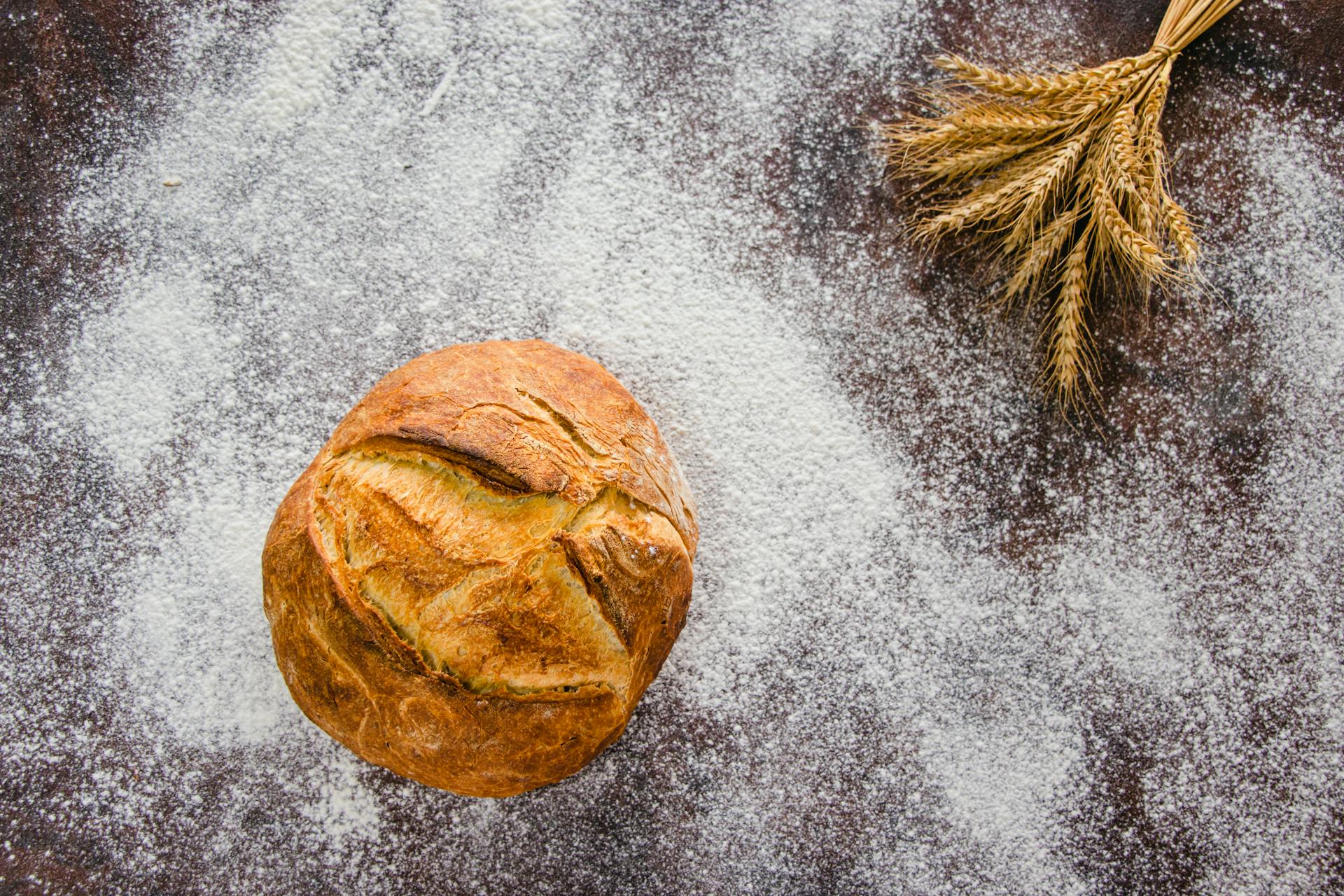 Artisan bread on a flour-dusted surface with wheat stalks, capturing the essence of baking.