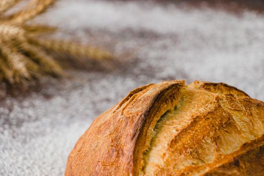 Freshly baked crusty bread with flour and wheat stalks for a rustic look.