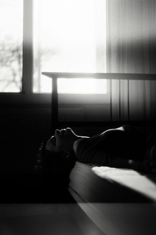 Free Silhouette of a woman lying in a sunlit room, creating a serene atmosphere. Stock Photo