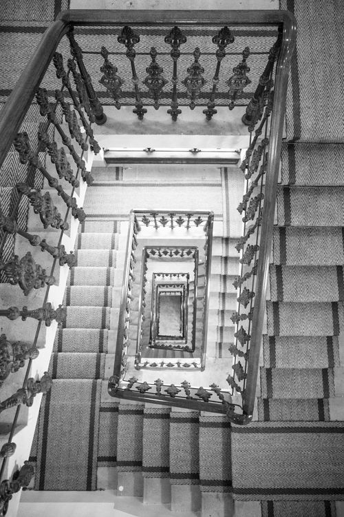 Free A mesmerizing top view of a classic spiral staircase with ornate railings captured in black and white. Stock Photo