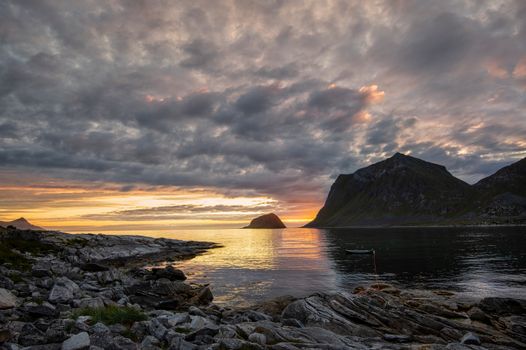 Stunning seascape with dramatic sunset sky over a rocky coastline and calm ocean waters.