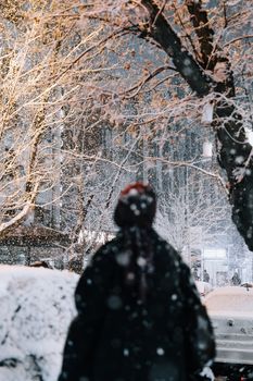 A person stands in a snowy Ankara street at night, surrounded by snow-covered trees.