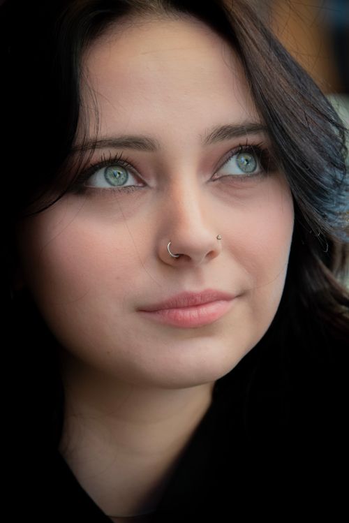 Free Close-up portrait of a woman with green eyes and nose rings, looking thoughtful. Stock Photo