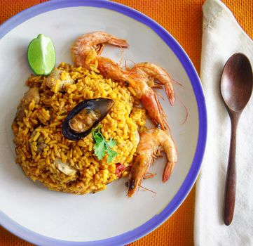 Close-up of a traditional seafood paella with shrimp and lime, perfect for food enthusiasts.