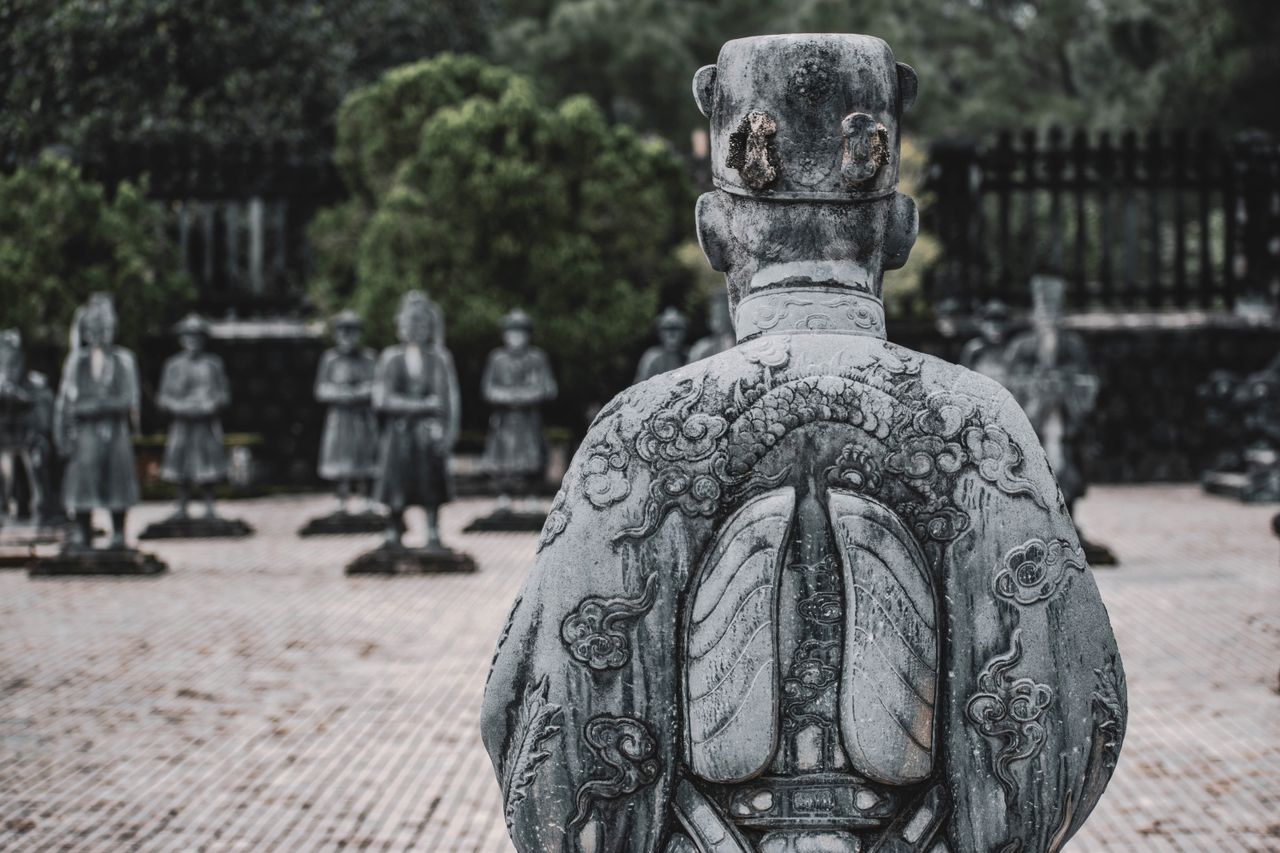 back view of an intricately carved stone warrior statue among others i